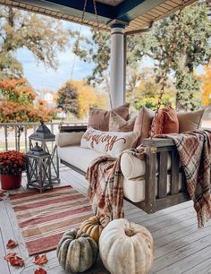 a porch covered in fall decorations and pumpkins