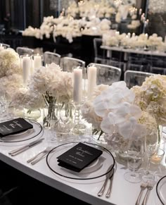 the table is set with white flowers and candles for an elegant wedding reception in black and white