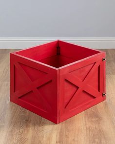 a red box sitting on top of a hard wood floor next to a white wall