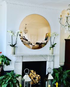 a living room filled with furniture and a fire place covered in plants next to a mirror