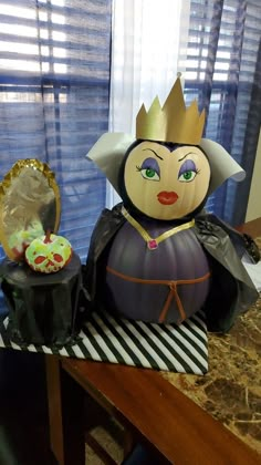 a table topped with a cake covered in frosting and a statue of an evil queen