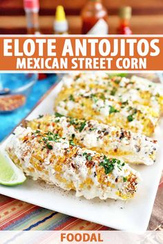 mexican street corn is served on a white plate with lime wedges and cilantro