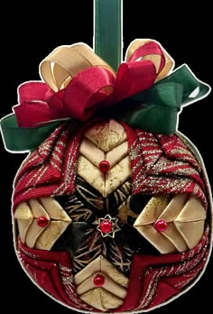 a red and gold ornament hanging from a green ribbon