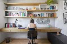 a woman sitting at a desk in front of a book shelf with books on it