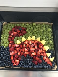 a tray with grapes, strawberries and blueberries arranged in the shape of a fish