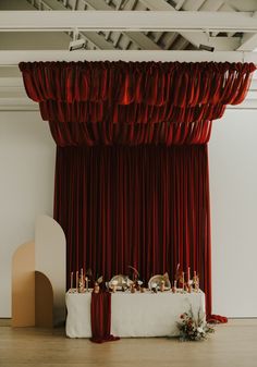 the table is set up in front of red drapes