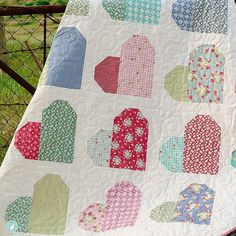 a quilted blanket with hearts on it sitting in front of a fenced area