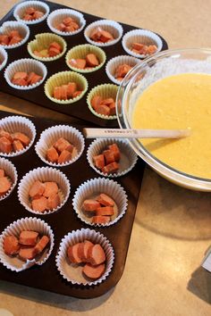 cupcake tins filled with carrots sitting on top of a counter next to a bowl of batter