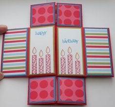 a hand holding an open birthday card with candles