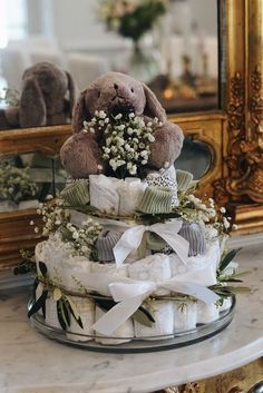 a teddy bear sitting on top of a diaper cake with baby's breath