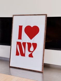 a red and white poster with the word i love ny in it next to a fireplace