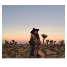 a woman in a hat and fur coat posing for a photo with a cactus background