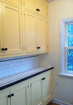 an empty kitchen with white cabinets and black counter tops in front of a large window