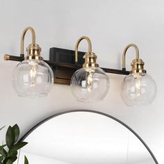 three clear glass globe lights are mounted on the wall above a mirror in a bathroom