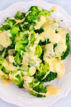 broccoli covered in cheese sauce on a white plate