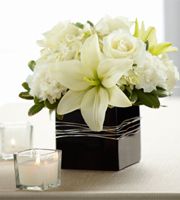 an image of a vase with white flowers on it and candles in the background for sale