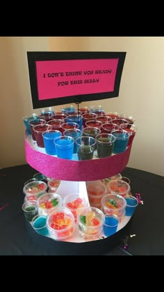 a table topped with cups filled with different colored drinks and candies on top of each other