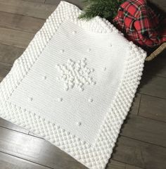 a white crocheted blanket sitting on top of a wooden floor next to a christmas tree