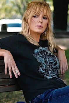 a woman sitting on top of a wooden bench