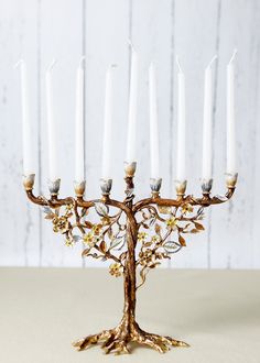 a candle holder with five candles in it on a table next to a white wall