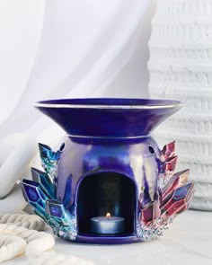 a blue vase sitting on top of a table next to a white towel and candle