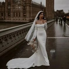 a woman in a wedding dress standing on a bridge