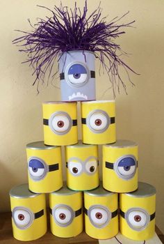 there is a tower made out of toilet paper with minion faces on it and purple feathers sticking out of the top