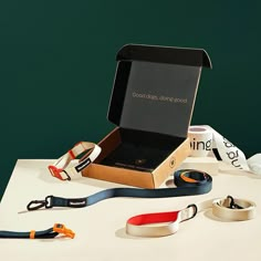 an open box with various lanyards sitting on top of a white table next to other items