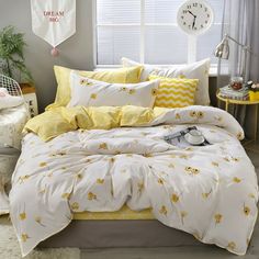 a bed with yellow and white comforters in a bedroom next to a window on the floor