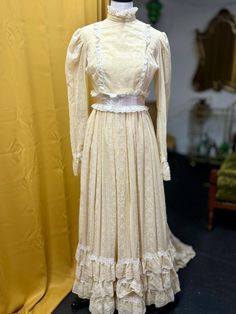 1970s floral curtain like wedding gown. Beige base with white floral and lace details around the hem, cuffs, bust, and neckline. Zip up back with hook and eye /clasps by the waist and neck. Clasps by the cuffs. Both armpits are torn, the left sleeve worse than the right.   A few small spots of discoloration (pictured) on the front of the gown. Bust: 34" Waist: 29" Length: 60" Train: 13" veil is at least 8ft long tulle! 3 holes in the veil (pictured) Cream Floor-length Gown With Lace Trim, Beige Victorian Wedding Dress With Ruffles, Regency Style Prairie Dress With Fitted Bodice For Wedding, Cream Vintage Dress For Wedding, Beige Ruffled Vintage Dress For Wedding, Cream Floor-length Vintage Dress For Wedding, Cream Vintage Floor-length Wedding Dress, Cream Floor-length Vintage Wedding Dress, Fitted Beige Victorian Wedding Dress