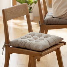 two wooden chairs with cushions on them in a living room or dining area, side by side