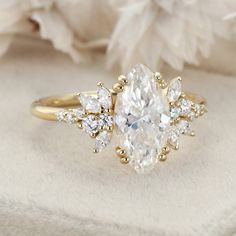 a ring with an oval cut diamond surrounded by smaller round and pear shaped diamonds on top