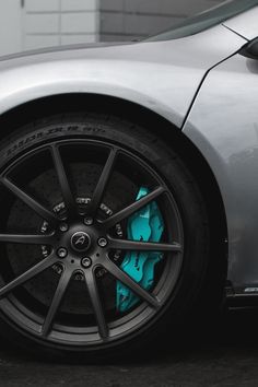 the front wheel of a silver sports car with blue brake pads and black rims