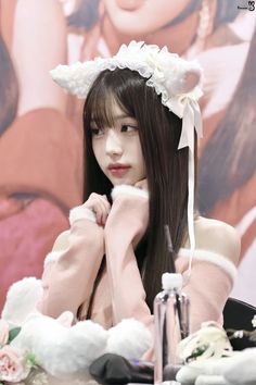 a woman with long hair wearing a white flowered headband sitting at a table