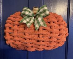 an orange pumpkin shaped door hanger with a green bow on it's front