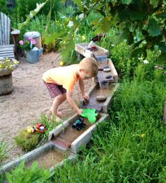 a little boy playing with toys in the grass near some steps and plants on the ground