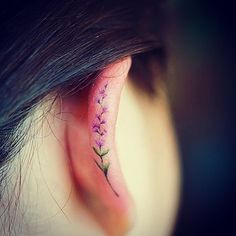 a woman's behind the ear tattoo with pink flowers on her left side piercing