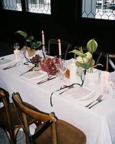 a long table with candles and flowers on it is set up for a formal dinner