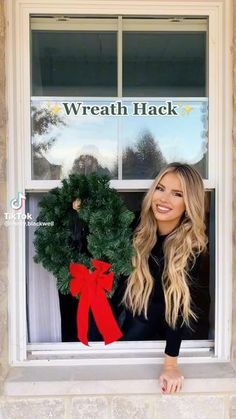 a woman holding a wreath in front of a window