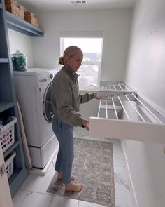 a woman standing in front of a dryer holding the door open to her new laundry room