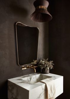 a bathroom sink sitting under a mirror next to a lamp and a potted plant