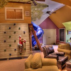 a living room filled with lots of furniture next to a wall mounted climbing wall on the ceiling