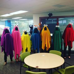 a group of people dressed up in colorful ponchles and scarves standing around a table