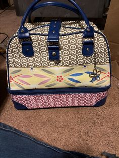 a handbag sitting on the floor next to a pair of jeans