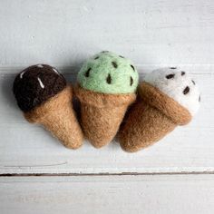 three ice cream cones with chocolate and green toppings on them, hanging from the side of a white wall