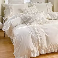 a white bed with ruffled sheets and pillows