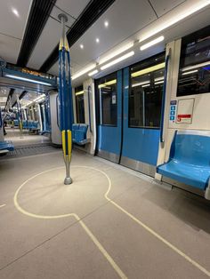 an empty subway car with blue seats and yellow poles on the floor in front of it