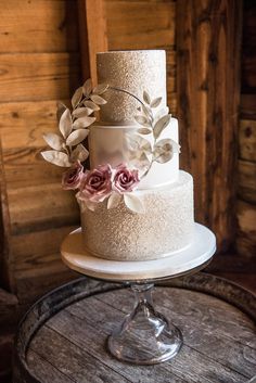 a three tiered wedding cake with pink flowers on the top and silver icing