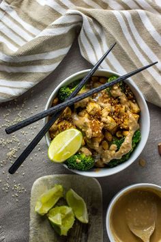 a bowl filled with broccoli, cauliflower and other foods next to some chopsticks