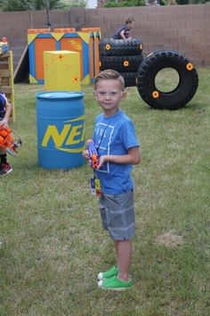 a young boy standing in the grass holding a toy